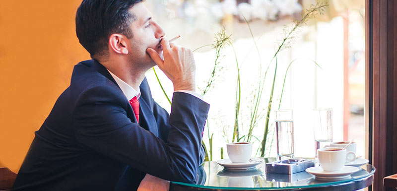 Homme dans un café fumant une cigarette